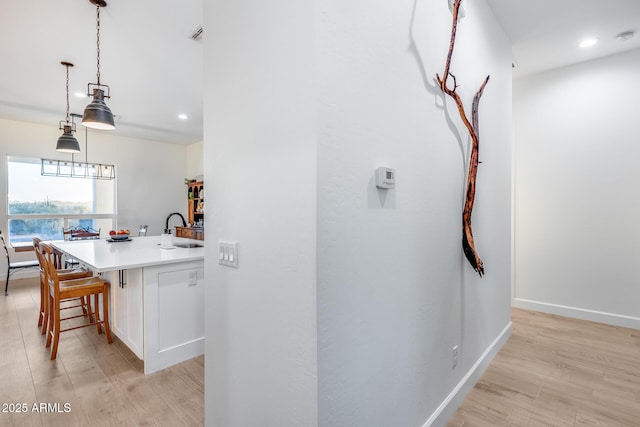 interior space with recessed lighting, a sink, light wood-style flooring, and baseboards