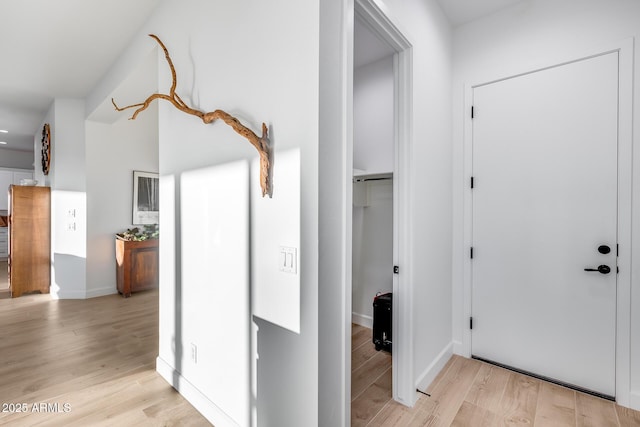 hallway featuring light wood-type flooring and baseboards