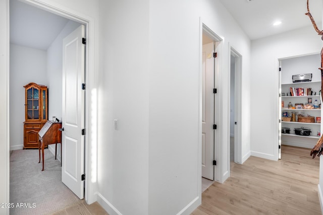 hallway featuring light wood finished floors, baseboards, and recessed lighting