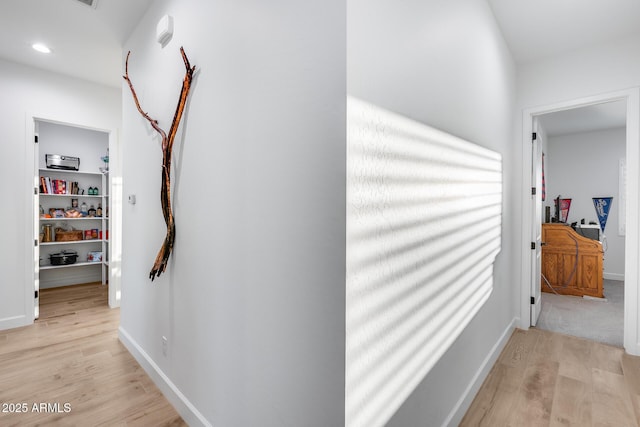 corridor featuring light wood finished floors, recessed lighting, and baseboards