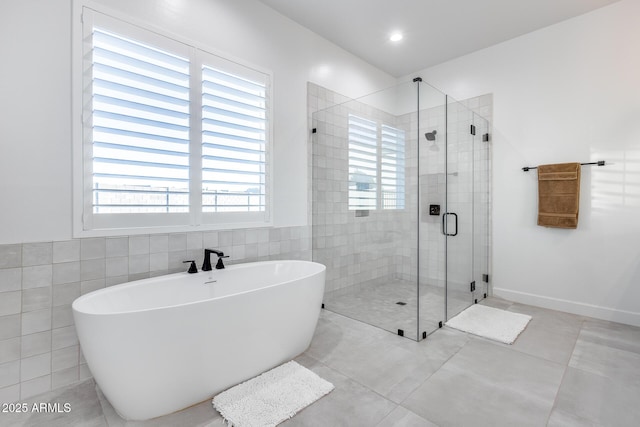 bathroom featuring a stall shower, a freestanding tub, tile walls, and tile patterned floors