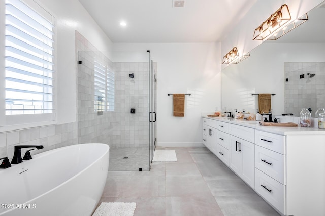 full bath with tile patterned flooring, a freestanding bath, a shower stall, and double vanity