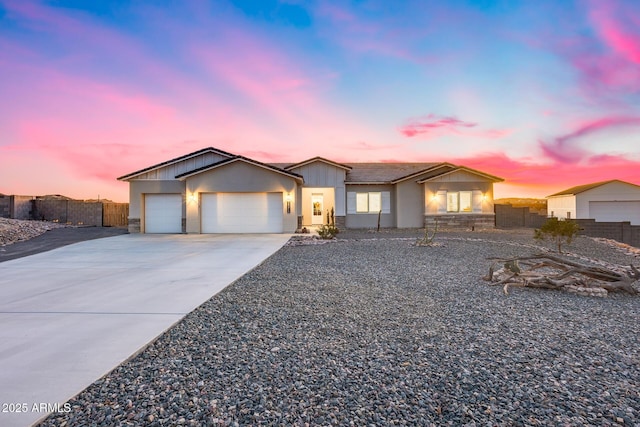 view of front of property featuring stone siding, an attached garage, fence, and driveway