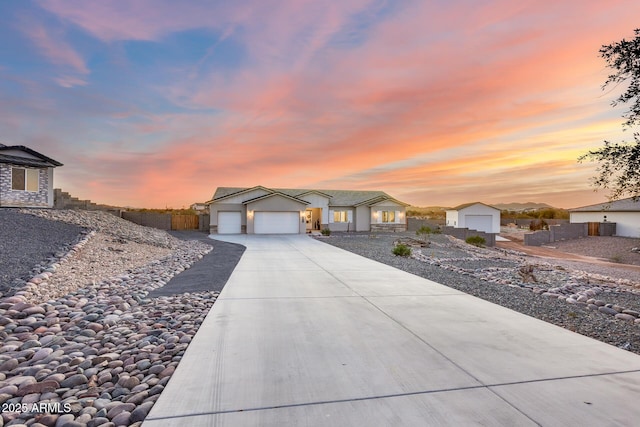 view of front of house with an attached garage, driveway, and fence