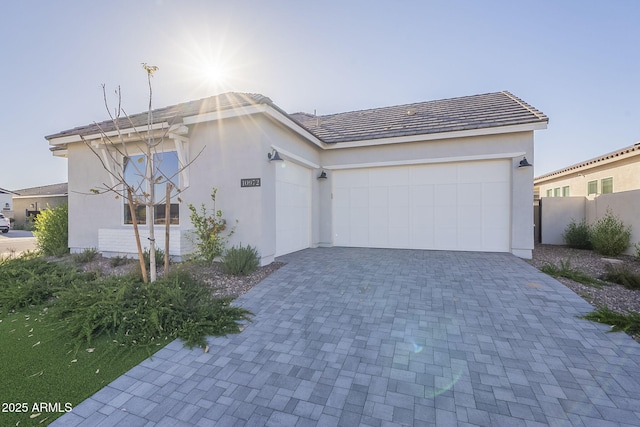 view of front of property featuring an attached garage, decorative driveway, and stucco siding