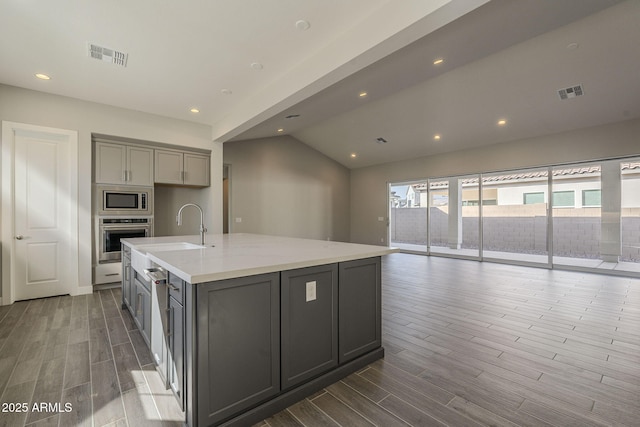 kitchen with appliances with stainless steel finishes, visible vents, a sink, and gray cabinetry