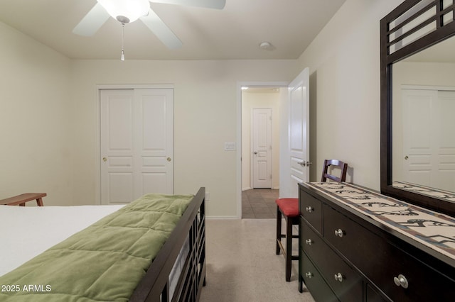 bedroom with light colored carpet, ceiling fan, and a closet