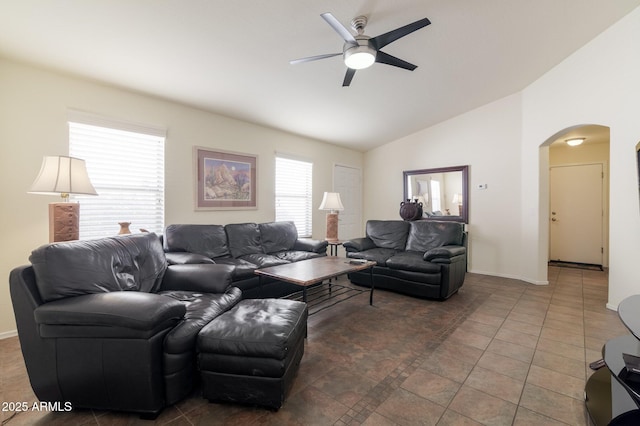 living room with ceiling fan, dark tile patterned flooring, and vaulted ceiling