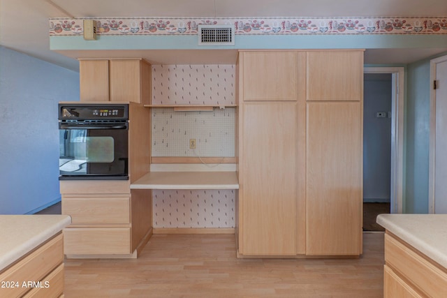 kitchen featuring light brown cabinets, oven, and light wood-type flooring