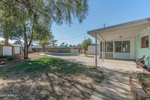 view of yard with a fenced in pool, a patio area, and a storage unit