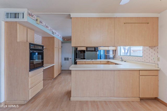 kitchen with light brown cabinets, black appliances, sink, light hardwood / wood-style floors, and kitchen peninsula