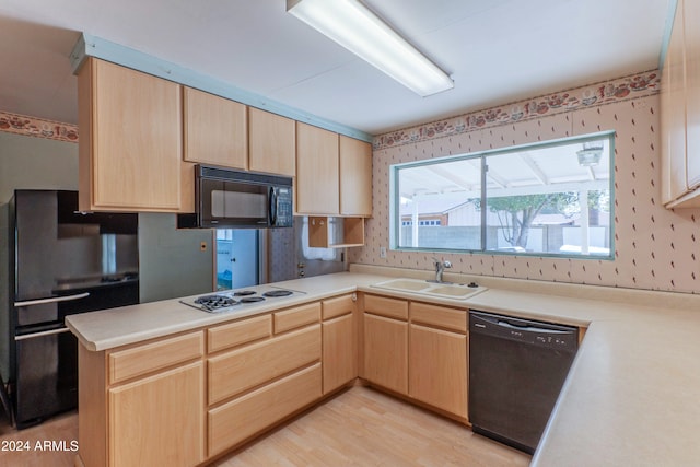 kitchen featuring light brown cabinets, black appliances, sink, light hardwood / wood-style flooring, and kitchen peninsula