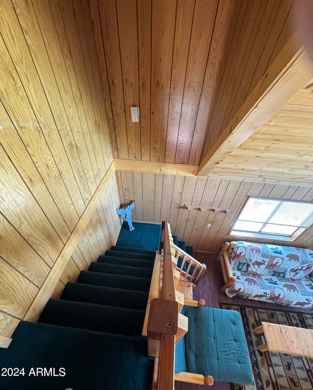 stairs with beamed ceiling, a skylight, wooden ceiling, and wood walls