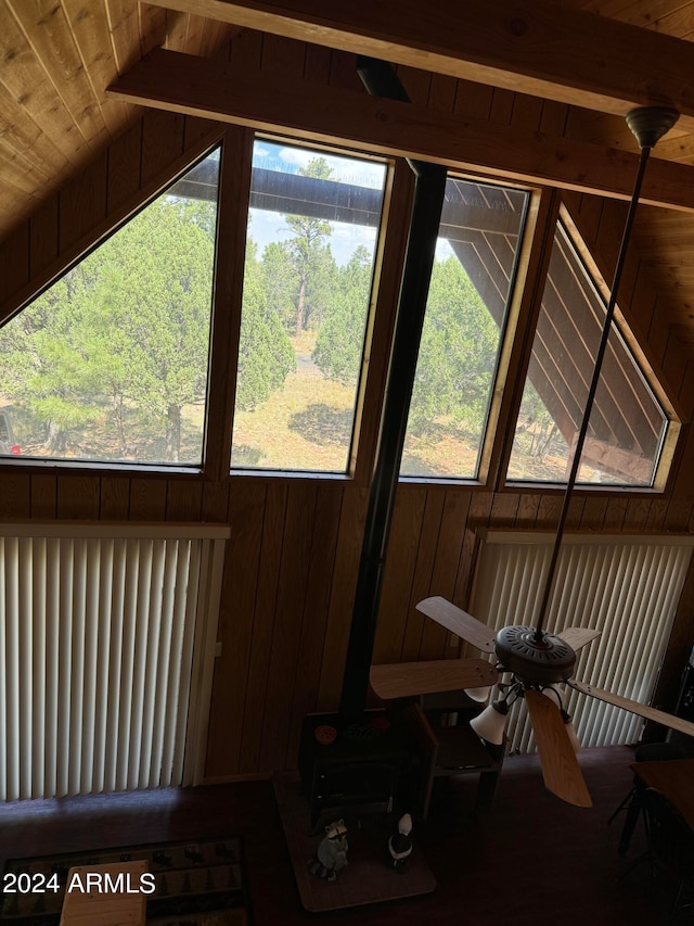 sunroom / solarium featuring vaulted ceiling with beams, a wealth of natural light, and a wood stove