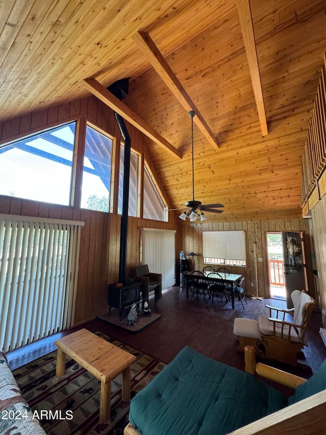 living room featuring wood walls, wood ceiling, wood-type flooring, a wood stove, and beamed ceiling