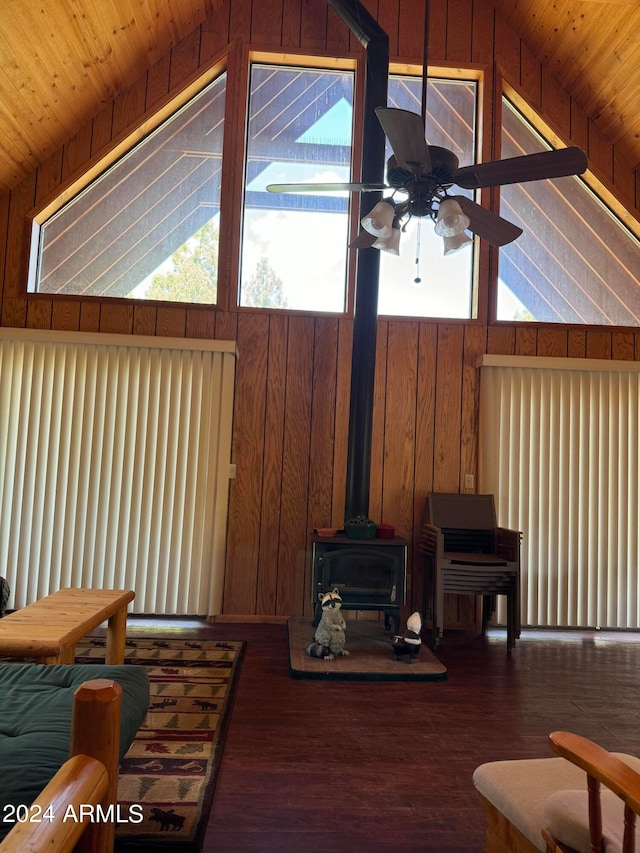 living room featuring vaulted ceiling, wood-type flooring, a wood stove, and wooden walls