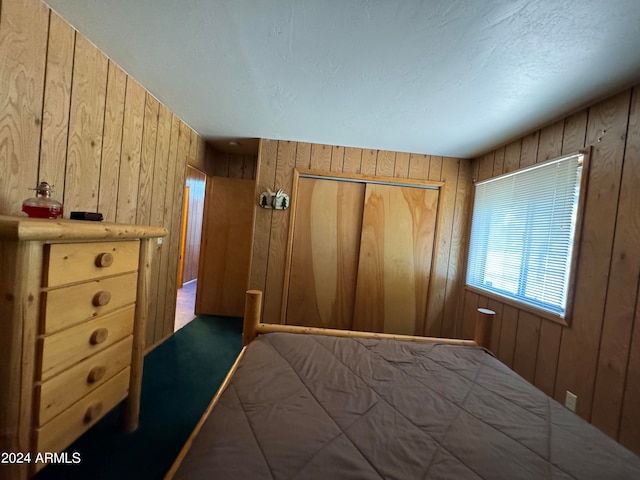 unfurnished bedroom with wooden walls, a closet, and a textured ceiling