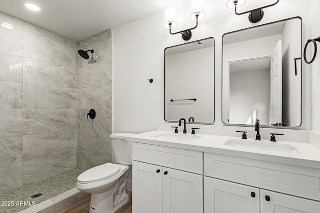 bathroom with tiled shower, vanity, and toilet