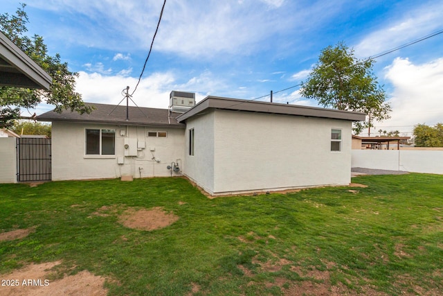 back of property featuring central AC unit and a yard