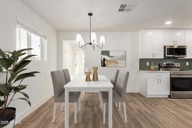 dining area featuring light wood-type flooring and a notable chandelier