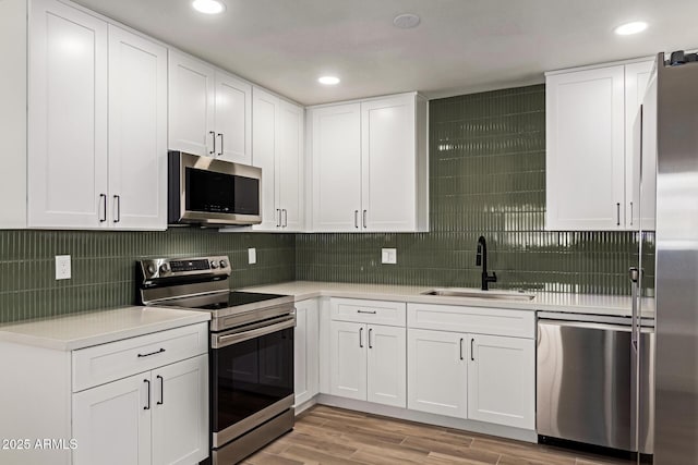 kitchen with white cabinets, stainless steel appliances, light hardwood / wood-style floors, and sink