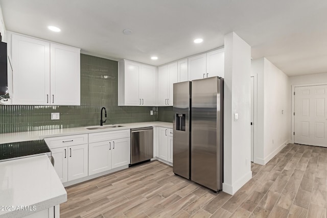 kitchen with stainless steel appliances, white cabinets, sink, and backsplash