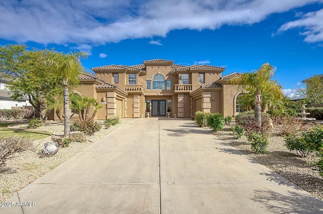 mediterranean / spanish home with a tiled roof, concrete driveway, stucco siding, french doors, and a garage