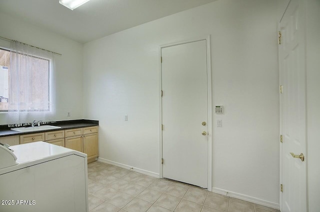 kitchen with light brown cabinetry, a sink, dark countertops, baseboards, and washer / dryer