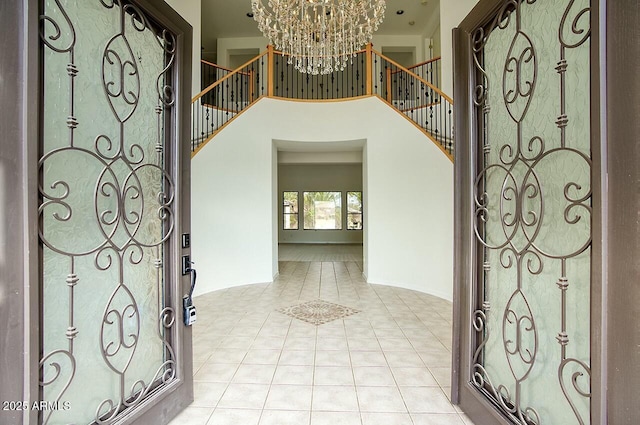 entryway featuring light tile patterned floors, an inviting chandelier, a towering ceiling, and stairs