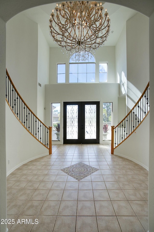 tiled entrance foyer with stairs, french doors, baseboards, and a chandelier