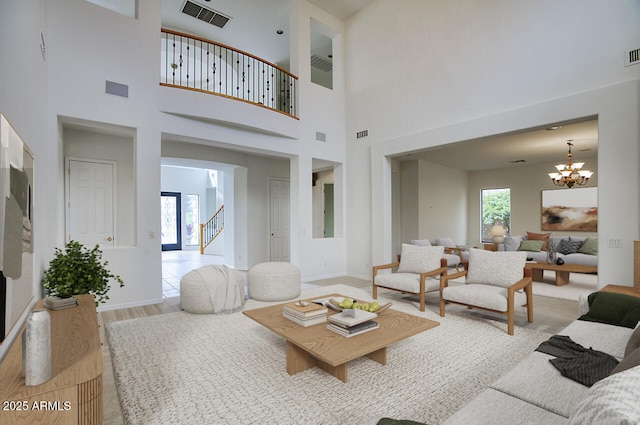 living room with a wealth of natural light, stairway, an inviting chandelier, and wood finished floors