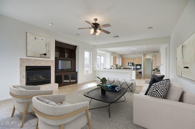 living area featuring visible vents, a tile fireplace, baseboards, and a ceiling fan