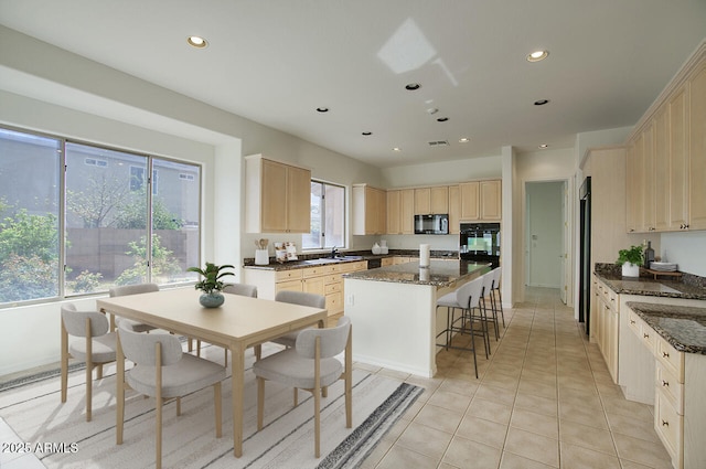 kitchen featuring light brown cabinets, recessed lighting, a sink, black microwave, and a center island