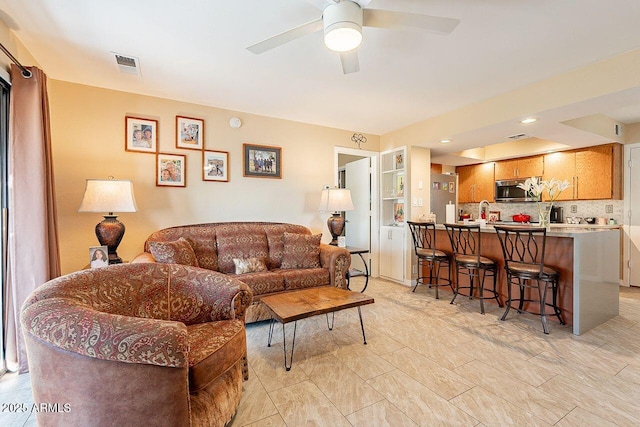 living area with a ceiling fan and visible vents