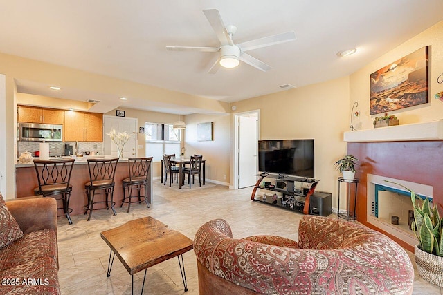 living room with ceiling fan, visible vents, and baseboards