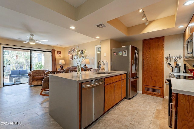 kitchen featuring stainless steel appliances, a sink, visible vents, open floor plan, and a tray ceiling