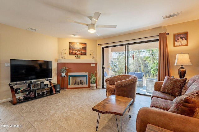 living room featuring visible vents, a fireplace, baseboards, and ceiling fan