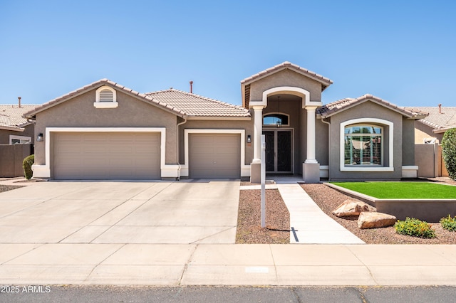 mediterranean / spanish house featuring an attached garage, concrete driveway, a tile roof, and stucco siding
