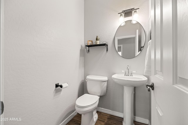bathroom with a sink, baseboards, toilet, and wood finished floors