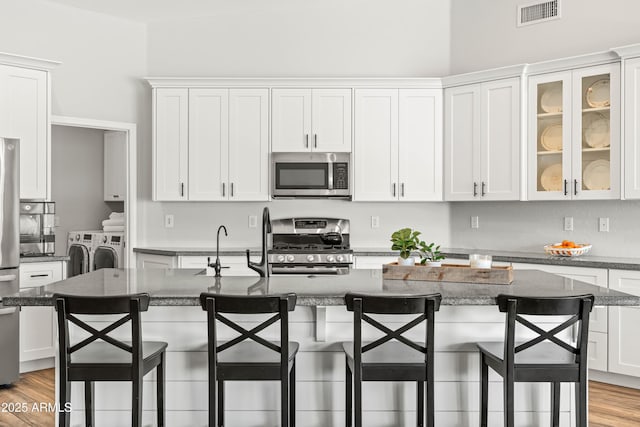 kitchen featuring washing machine and clothes dryer, stainless steel appliances, white cabinets, and visible vents
