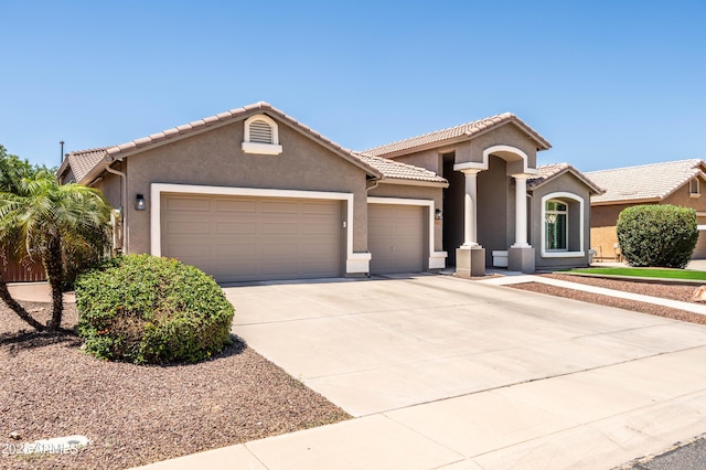 mediterranean / spanish house with a garage, stucco siding, driveway, and a tiled roof