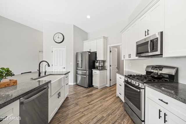 kitchen featuring dark stone counters, stainless steel appliances, white cabinetry, and dark wood-style flooring