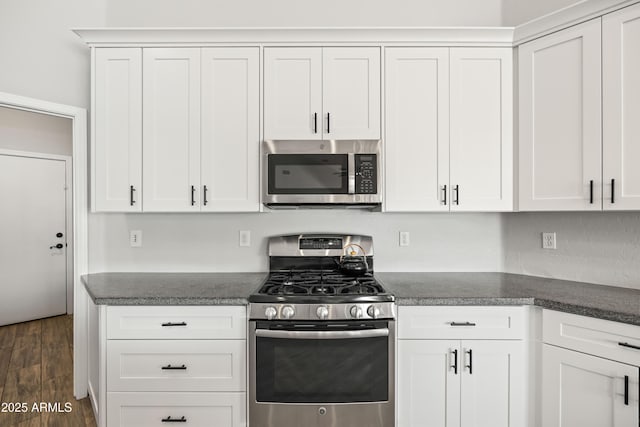 kitchen with white cabinets, dark countertops, appliances with stainless steel finishes, and dark wood-type flooring