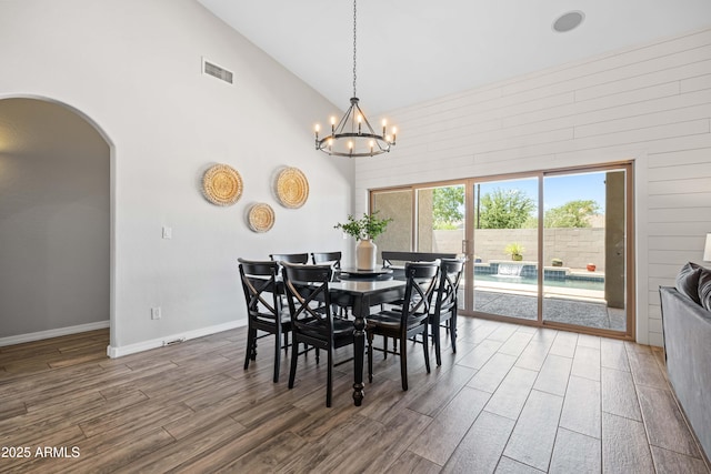dining room featuring arched walkways, a chandelier, wood finished floors, and visible vents