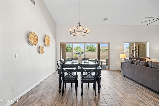 dining area featuring wood walls, a chandelier, wood finished floors, and visible vents