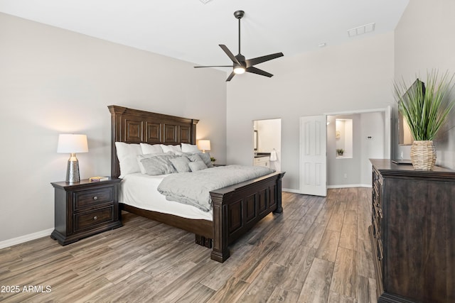 bedroom featuring high vaulted ceiling, baseboards, light wood finished floors, and visible vents
