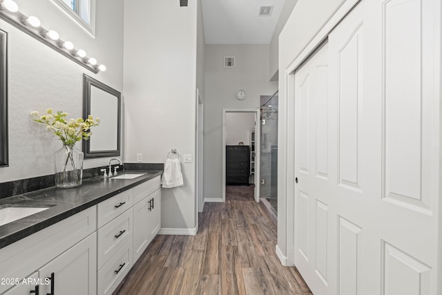bathroom with a sink, baseboards, double vanity, and wood finished floors