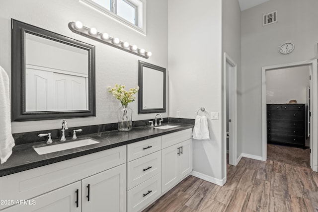 full bath featuring visible vents, a sink, wood finished floors, and double vanity