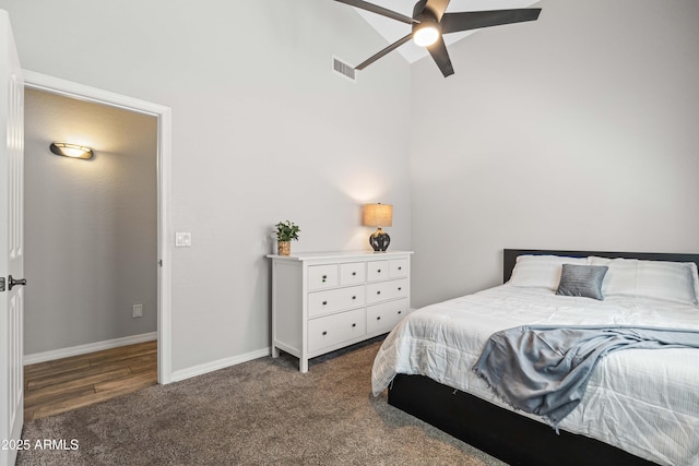 carpeted bedroom with ceiling fan, a high ceiling, visible vents, and baseboards