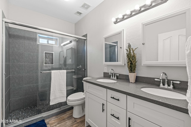 full bathroom featuring double vanity, a sink, toilet, and a shower stall